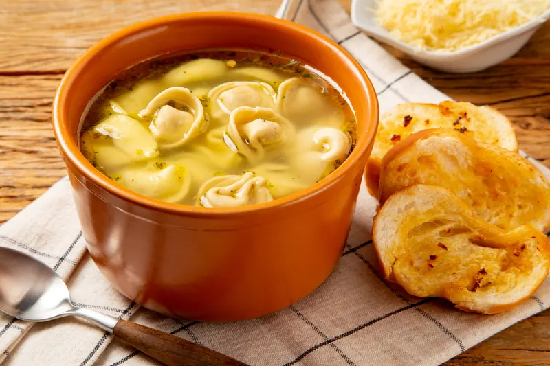 Capeletti in brodo em cumbuca de cerâmica com torradinhas