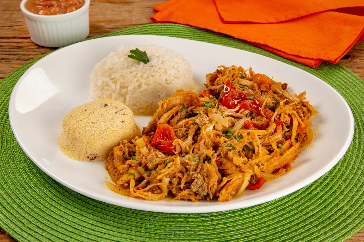 Prato de pernil desfiado com arroz e acompanhamento